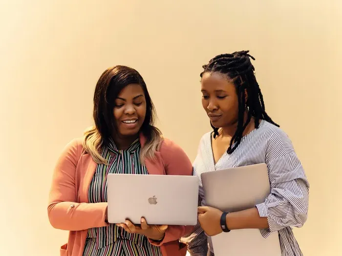 Two women entrepreneurs reviewing work on laptops, showing collaboration and growth supported by Local Biz Spot